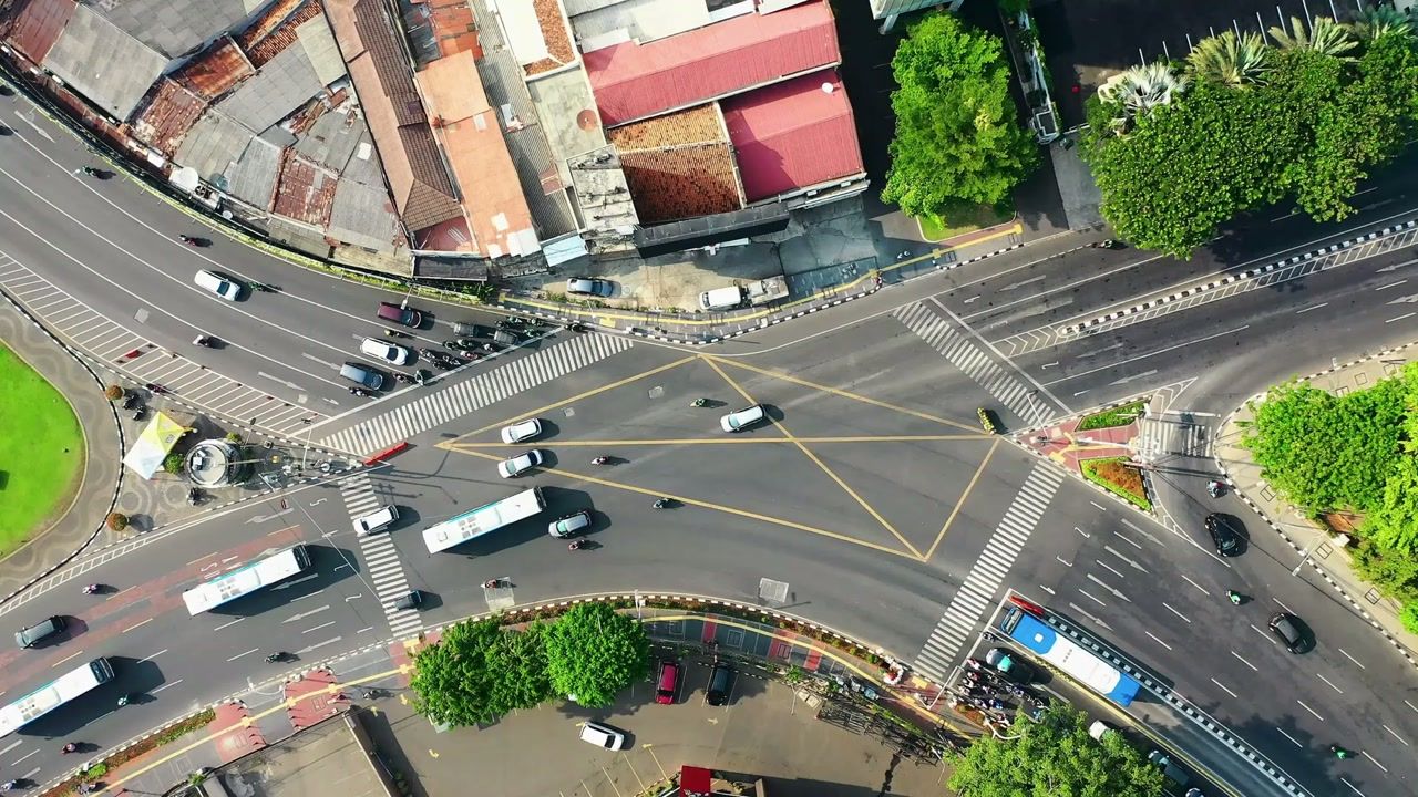 Drone view of a city road junction with cars and buses.