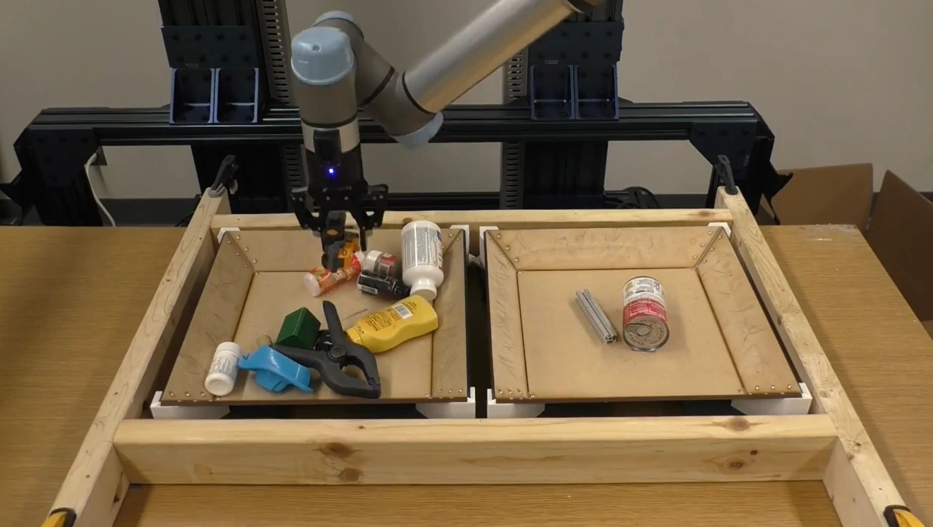 A robot arm picking household objects from a tray.